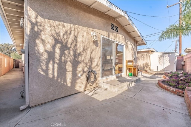 back of property featuring an outbuilding, stucco siding, a patio area, a shed, and a fenced backyard