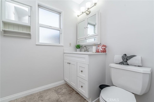 bathroom featuring toilet, baseboards, and vanity