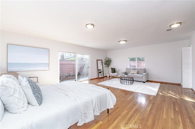 bedroom featuring access to exterior, visible vents, baseboards, and wood finished floors