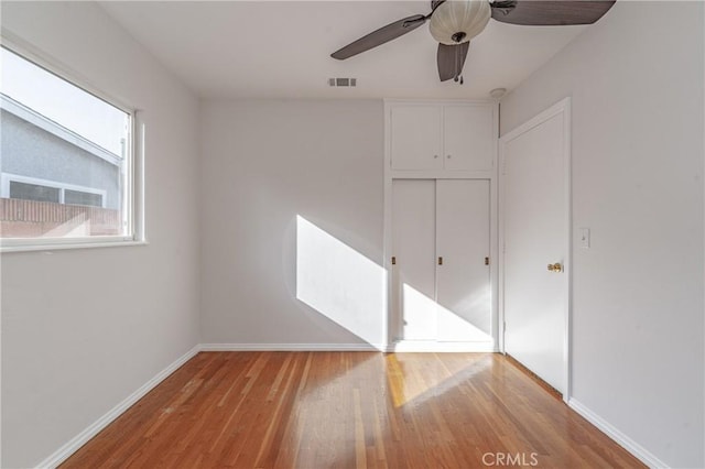 unfurnished bedroom with a ceiling fan, baseboards, visible vents, light wood-style floors, and a closet