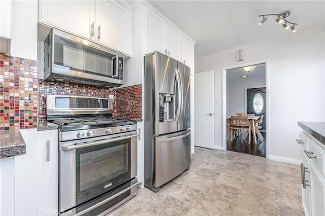 kitchen with white cabinetry, decorative backsplash, stainless steel appliances, and dark stone counters