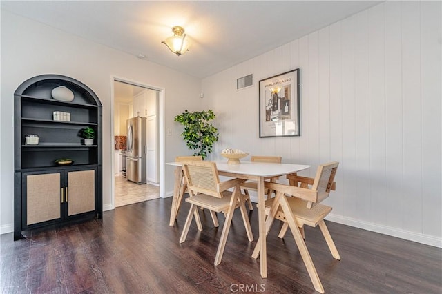 dining room with dark hardwood / wood-style flooring and built in features