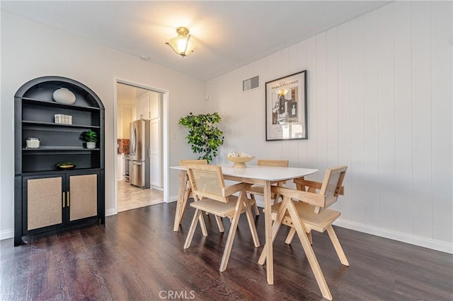 dining space featuring built in features, baseboards, visible vents, and dark wood-style flooring