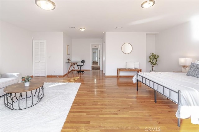 bedroom featuring baseboards, visible vents, and light wood finished floors