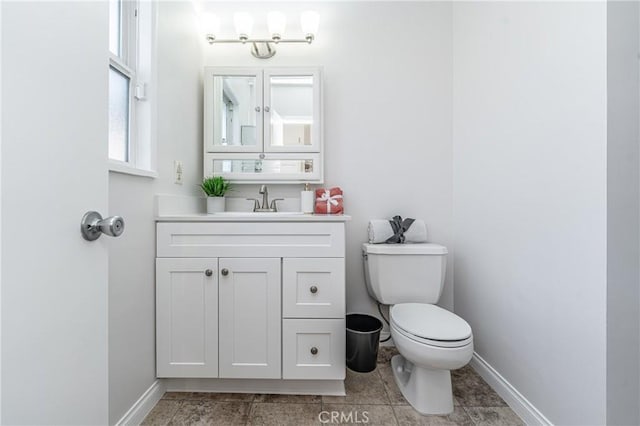 half bathroom with vanity, toilet, and baseboards