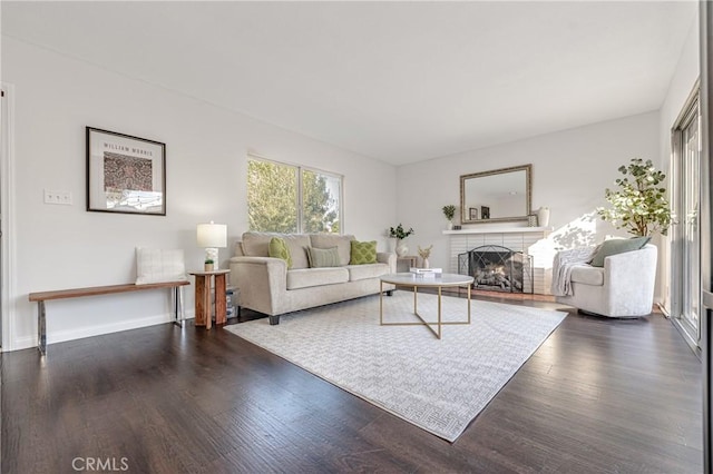 living room with a fireplace, baseboards, and wood finished floors