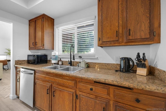 kitchen with light stone counters, dishwasher, sink, and light wood-type flooring