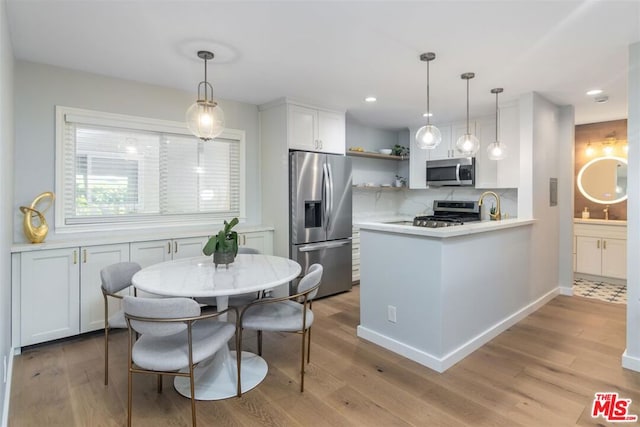 kitchen featuring white cabinetry, decorative backsplash, stainless steel appliances, and hanging light fixtures