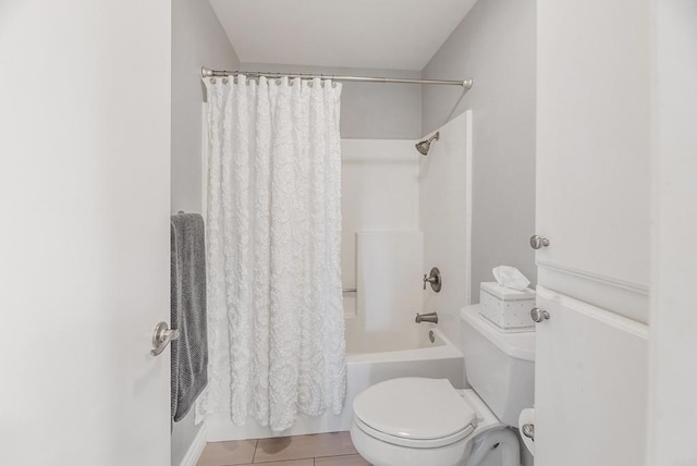 bathroom with shower / tub combo with curtain, tile patterned floors, and toilet