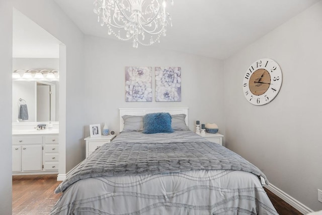 bedroom with dark wood-type flooring, ensuite bath, sink, and a notable chandelier