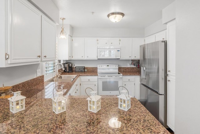 kitchen featuring sink, white appliances, white cabinetry, hanging light fixtures, and dark stone countertops