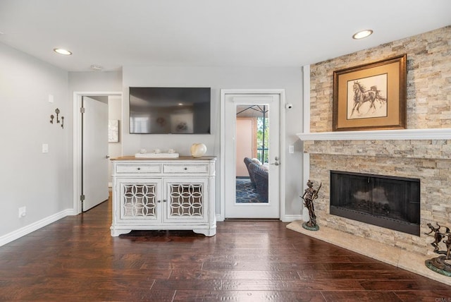 unfurnished living room featuring a stone fireplace and dark hardwood / wood-style flooring