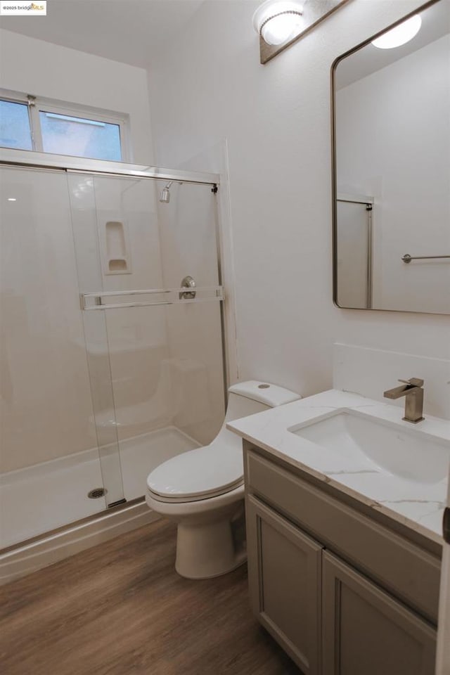 bathroom featuring wood-type flooring, toilet, an enclosed shower, and vanity