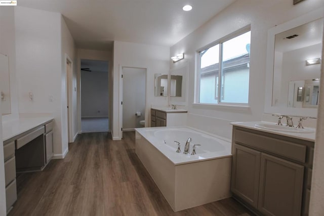 bathroom with vanity, wood-type flooring, toilet, and a bathing tub