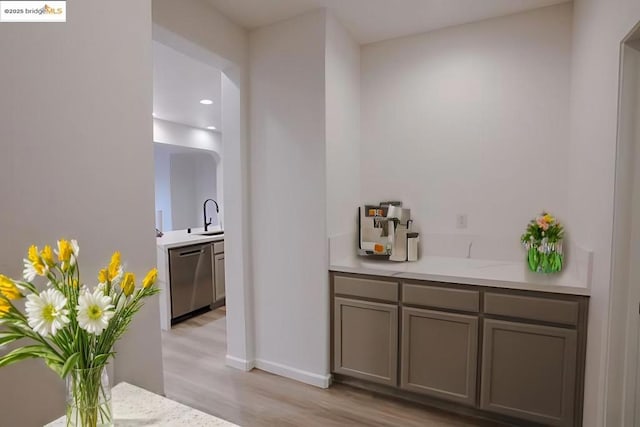 bar with gray cabinetry, dishwasher, sink, and light wood-type flooring