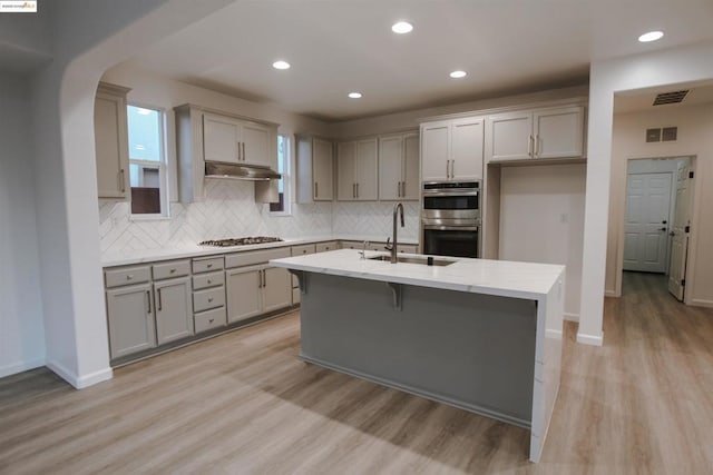 kitchen with a kitchen island with sink, sink, light hardwood / wood-style flooring, and stainless steel appliances