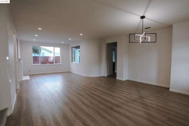 spare room featuring dark hardwood / wood-style flooring and a chandelier