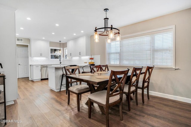 dining room with a notable chandelier, light hardwood / wood-style flooring, and sink