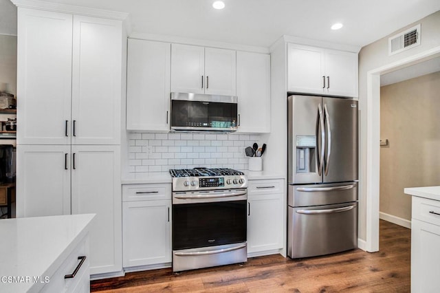 kitchen featuring appliances with stainless steel finishes, dark wood-type flooring, white cabinets, and decorative backsplash