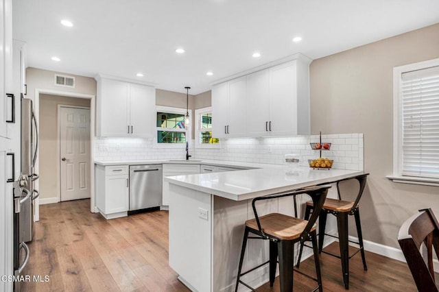 kitchen featuring white cabinetry, hanging light fixtures, kitchen peninsula, and appliances with stainless steel finishes