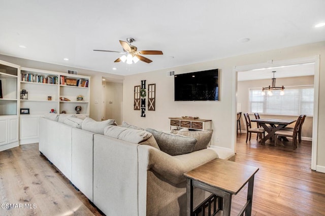 living room with ceiling fan with notable chandelier and light wood-type flooring