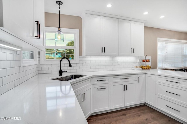 kitchen featuring sink, dark wood-type flooring, backsplash, white cabinets, and decorative light fixtures