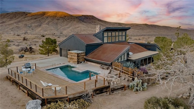 back house at dusk with a mountain view and a patio