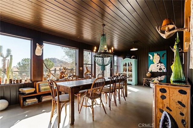 interior space with a mountain view, a notable chandelier, wooden ceiling, and concrete floors