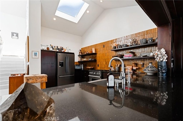 kitchen featuring high vaulted ceiling, a skylight, sink, kitchen peninsula, and stainless steel refrigerator with ice dispenser