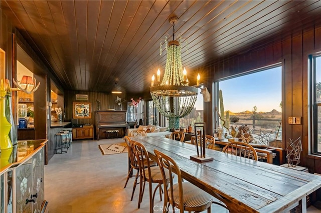 dining space with an inviting chandelier, wooden ceiling, and wood walls