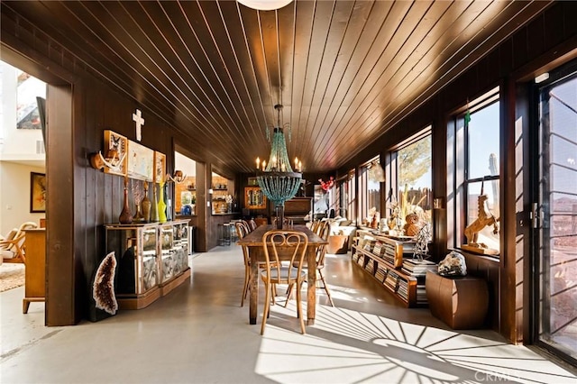 dining space featuring concrete flooring, wooden ceiling, and a chandelier