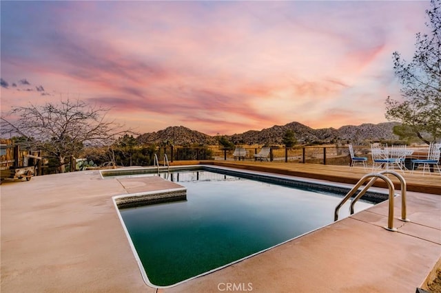 pool at dusk featuring a mountain view and a patio area