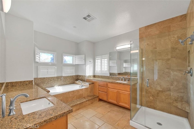 bathroom featuring visible vents, a sink, a shower stall, and a garden tub