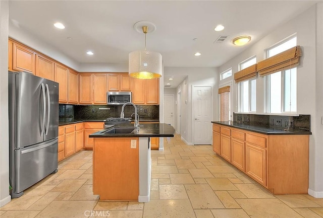 kitchen with an island with sink, sink, backsplash, hanging light fixtures, and stainless steel appliances