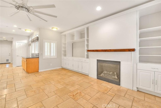 unfurnished living room featuring recessed lighting, a fireplace, a ceiling fan, baseboards, and stone tile flooring