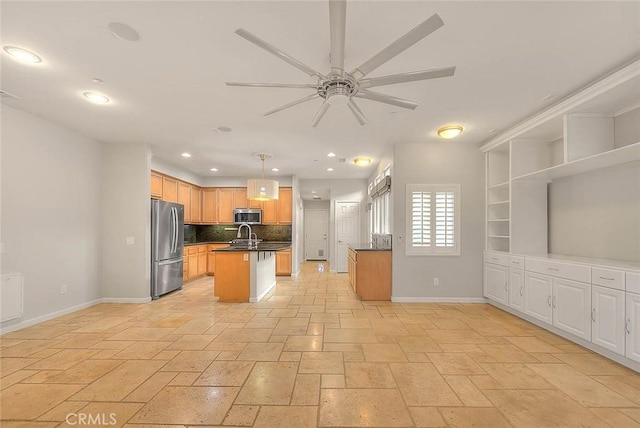 kitchen with stainless steel appliances, dark countertops, tasteful backsplash, a kitchen island with sink, and baseboards