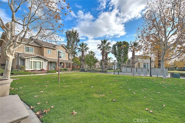 view of community featuring a yard, fence, and a residential view