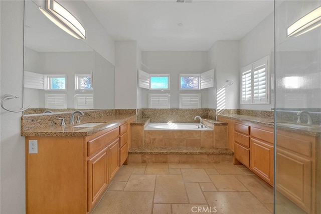 bathroom with a garden tub, two vanities, a sink, and stone tile flooring