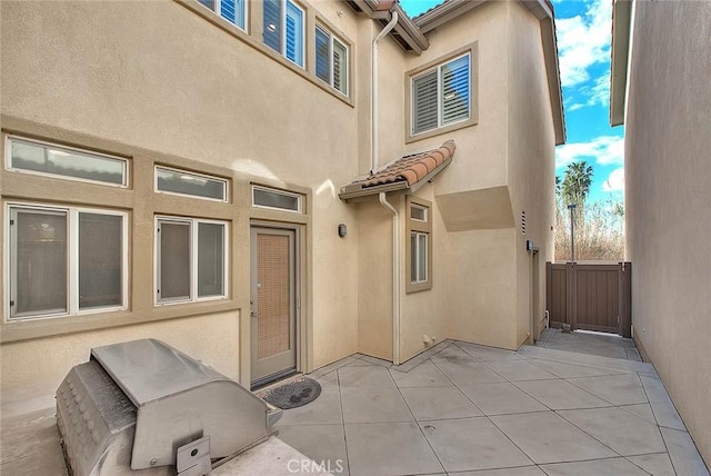 exterior space featuring a patio, a tile roof, and stucco siding