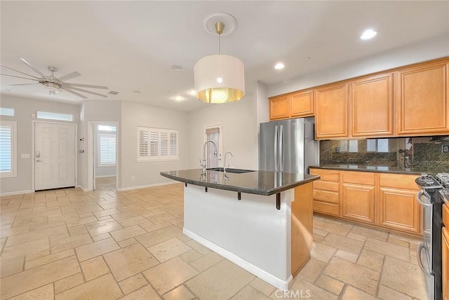 kitchen with recessed lighting, stone tile floors, stainless steel appliances, a sink, and baseboards