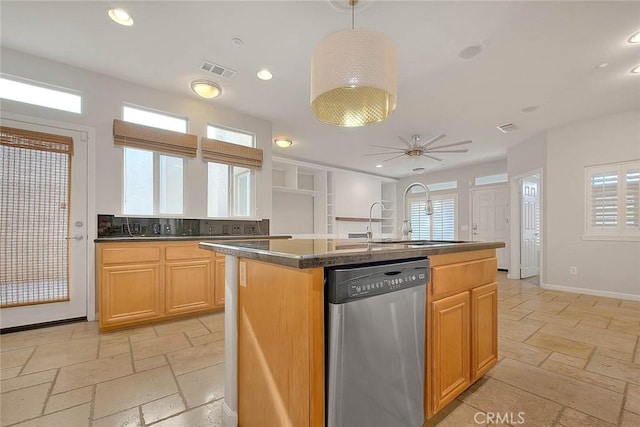 kitchen featuring stone tile floors, baseboards, dark countertops, stainless steel dishwasher, and recessed lighting