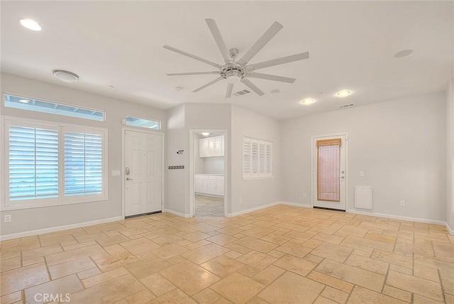 foyer with ceiling fan, stone tile floors, visible vents, and baseboards