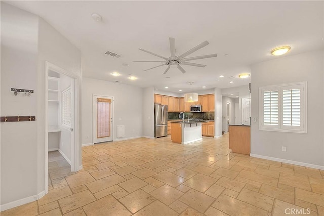 kitchen with visible vents, dark countertops, open floor plan, stainless steel appliances, and stone tile flooring