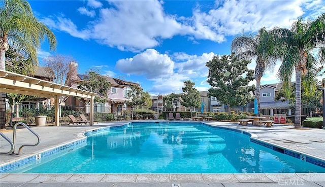 pool with a patio area, a residential view, and fence