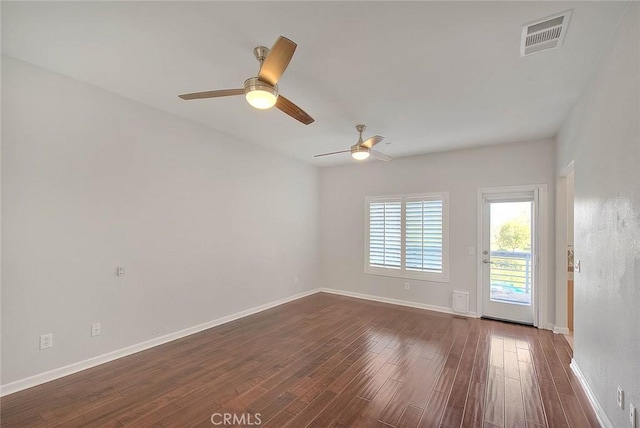 empty room with dark wood-style floors, visible vents, ceiling fan, and baseboards