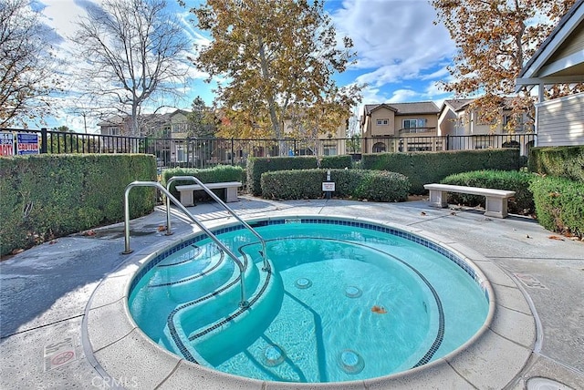 view of swimming pool with a patio area, fence, and a hot tub