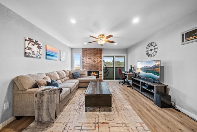 living room featuring a brick fireplace, ceiling fan, and light hardwood / wood-style flooring