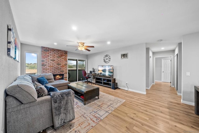 living room with plenty of natural light, light hardwood / wood-style flooring, ceiling fan, and a brick fireplace