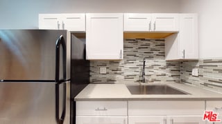 kitchen with white cabinetry, sink, and stainless steel refrigerator