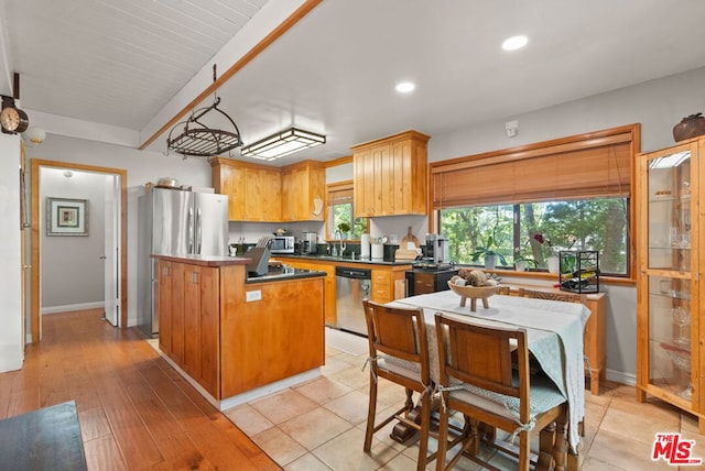 kitchen featuring beamed ceiling, sink, a center island, stainless steel appliances, and light hardwood / wood-style flooring